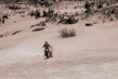 A powerful red dirt bike kicking up dust on a rugged trail