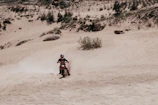 Drone shot of a dirt bike kicking up dust on a winding off-road trail.
