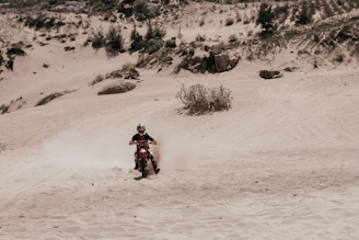 Enduro rider navigating a rocky mountain path with dust kicking up behind the bike.