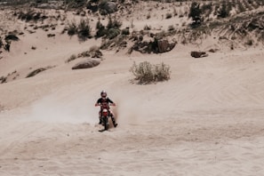 An action shot of a dirt bike kicking up dust on a rugged trail