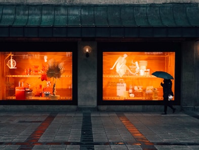 person walking and using umbrella near boutique