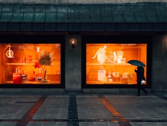 person walking and using umbrella near boutique