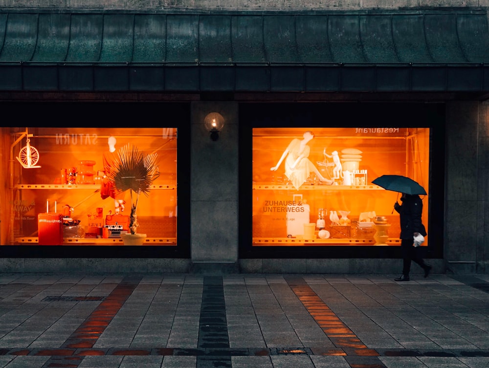 Persona caminando y usando paraguas cerca de boutique