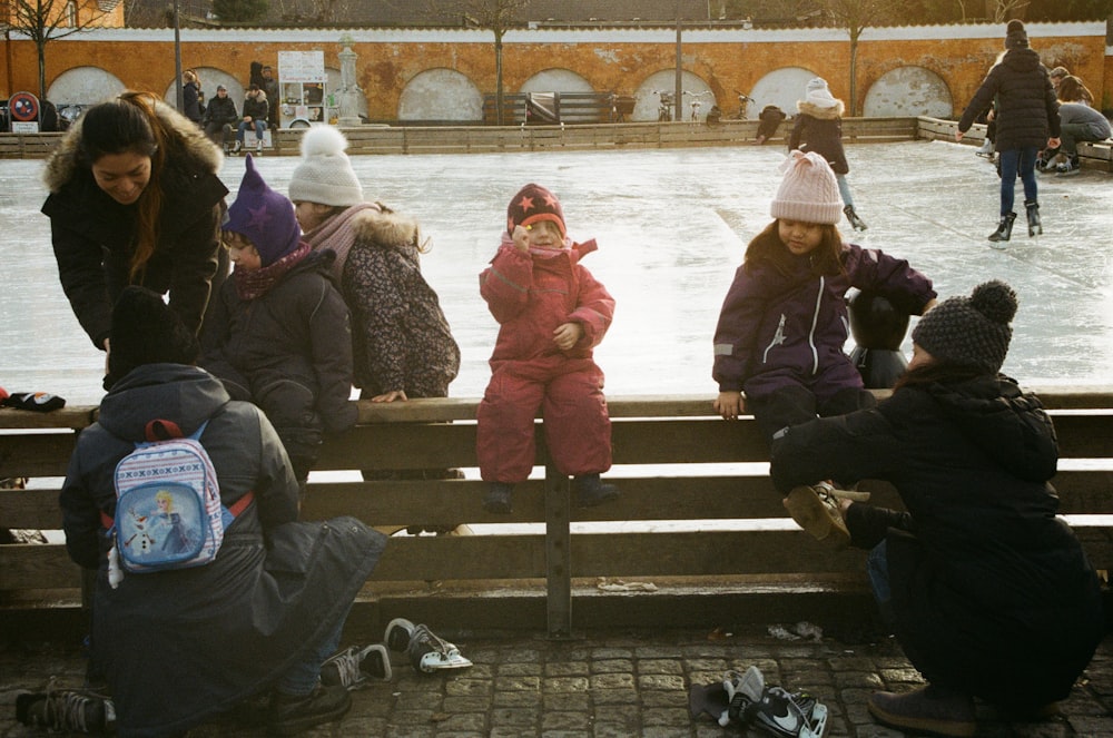 children sitting and others are ice skating on park