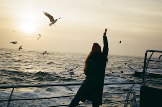 woman in boat playing with the birds flying at sea