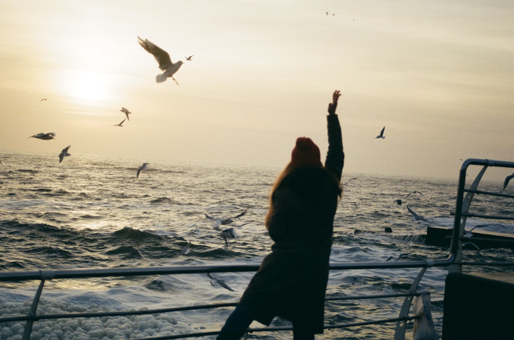 woman in boat playing with the birds flying at sea