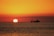 A serene sunset over the water, with a boat silhouetted against the colorful sky.