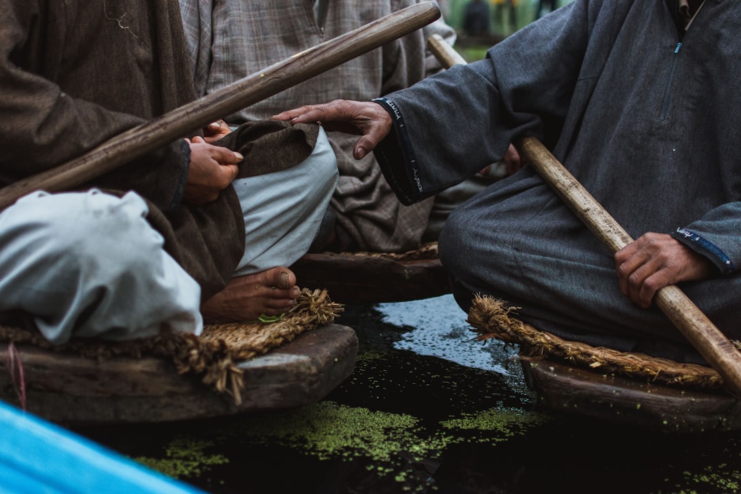 two person sitting and holding sticks