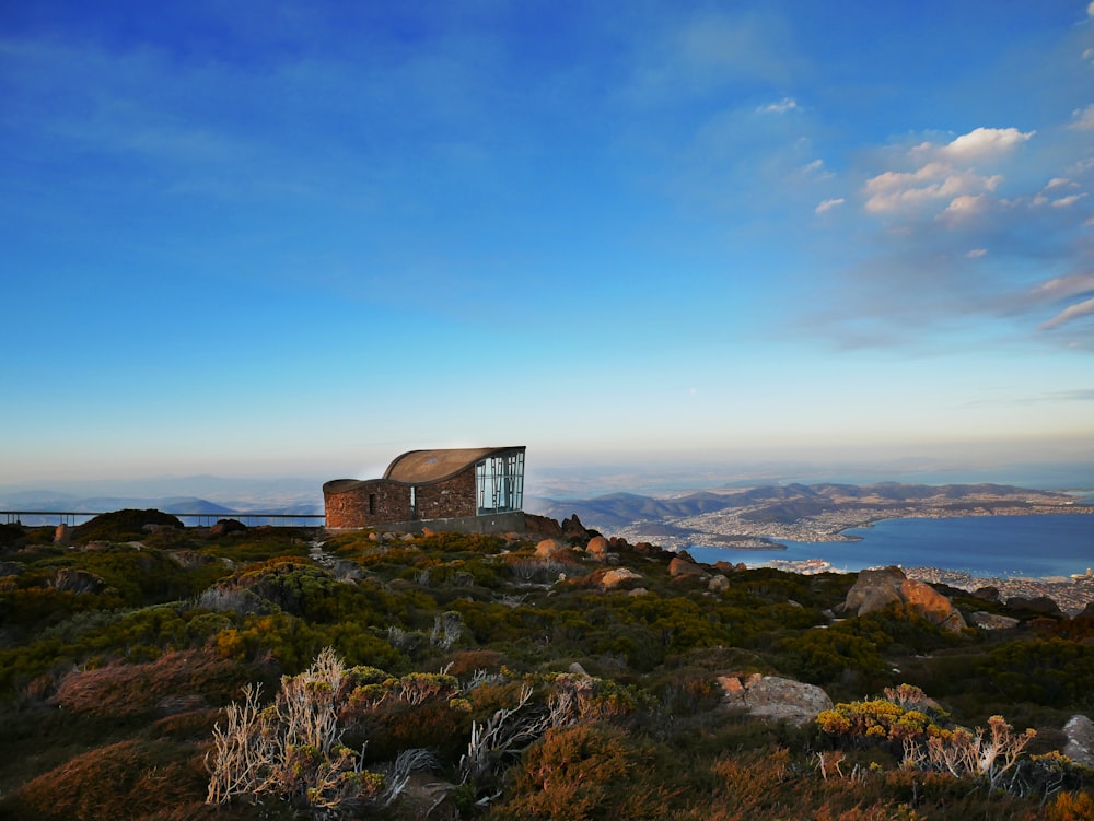 Casa de concreto marrom perto de colina rochosa sob céu azul e branco