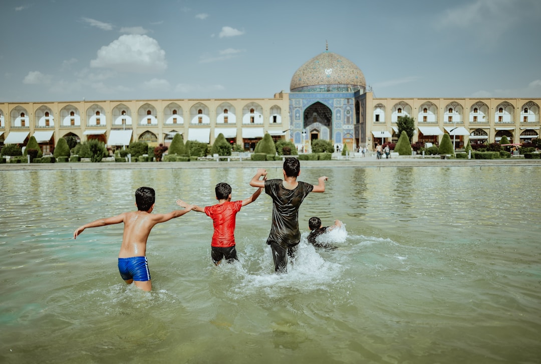 four kids on body of water beside concrete building during daytime