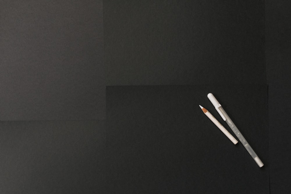 two white pens on black surface