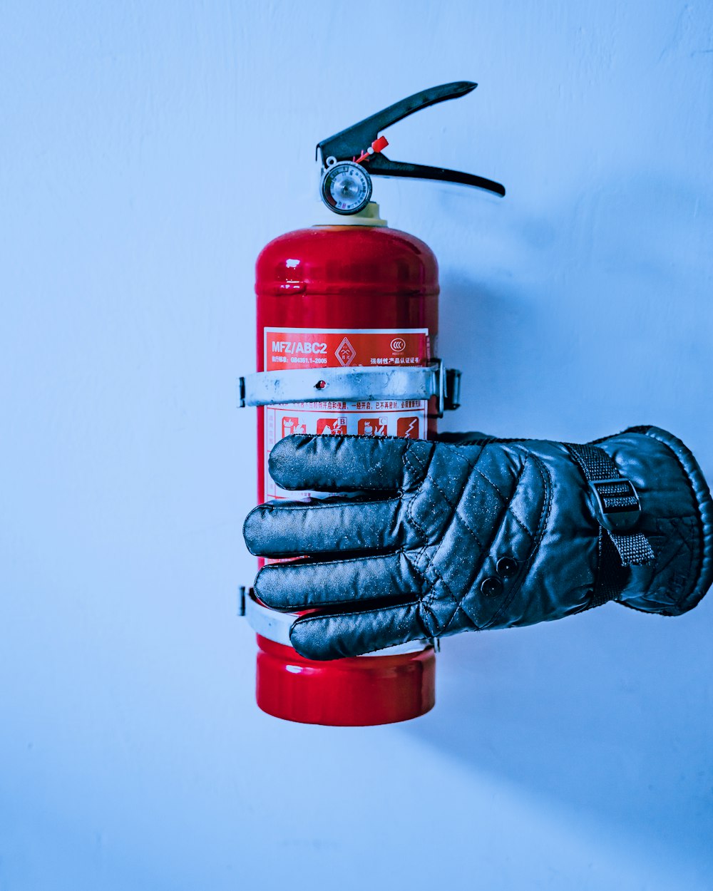 quilted blue gloves near red fire extinguisher