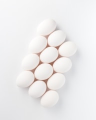 Close-up of glossy, perfectly shaped eggs arranged elegantly on a minimalist white surface.