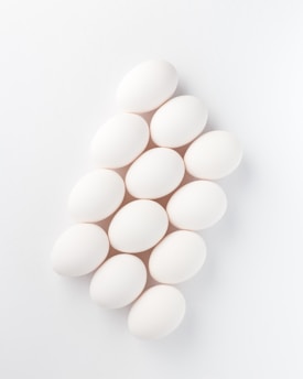 Close-up of glossy, perfectly shaped eggs arranged elegantly on a minimalist white surface.