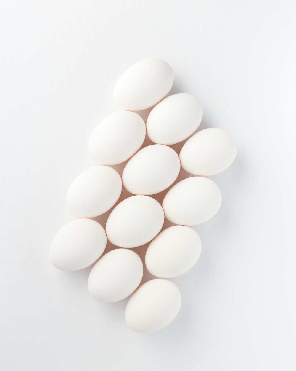 Zwölf weiße Eier auf weißer Oberfläche
