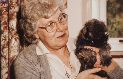 An elderly person enjoying time with their dog outdoors.