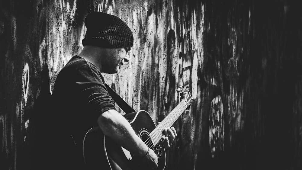 grayscale photo of man playing acoustic guitar