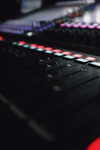 Close-up of a sleek mixing console illuminated by red and white LED lights, capturing the essence of high-end audio production.