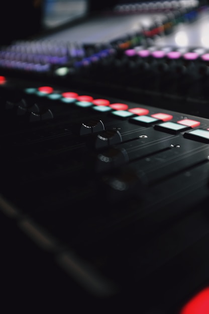 Close-up of a sleek mixing console illuminated by red and white LED lights, capturing the essence of high-end audio production.