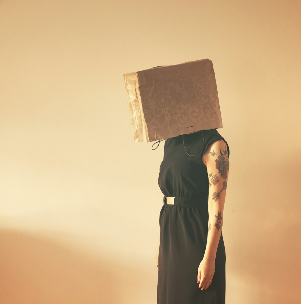 person in black sleeveless dress covered by paper bag