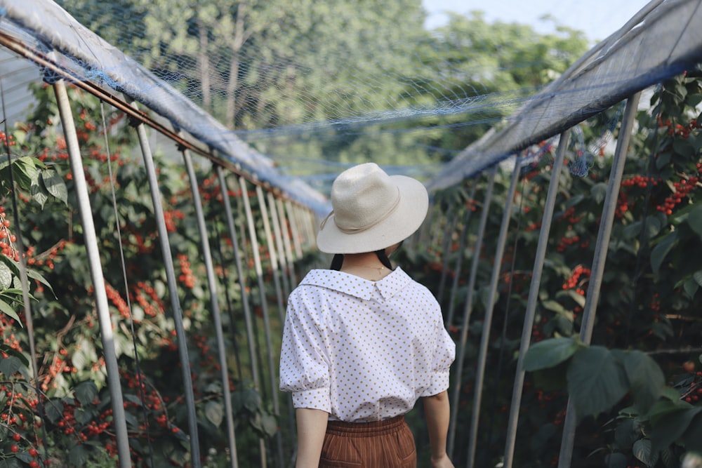 Une femme coiffée d’un chapeau marche sur une passerelle