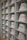 A neatly arranged display of white bucket hats sits on multiple shelves. Each hat is embroidered with words in different languages and colors, such as red, yellow, purple, and green. The hats are organized in a spacious, grid-like pattern within an indoor setting.