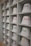 A neatly arranged display of white bucket hats sits on multiple shelves. Each hat is embroidered with words in different languages and colors, such as red, yellow, purple, and green. The hats are organized in a spacious, grid-like pattern within an indoor setting.