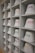 A neatly arranged display of white bucket hats sits on multiple shelves. Each hat is embroidered with words in different languages and colors, such as red, yellow, purple, and green. The hats are organized in a spacious, grid-like pattern within an indoor setting.