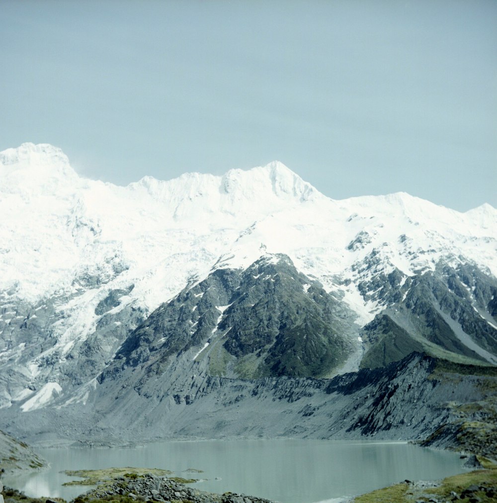 mountain covered with snow showing lake during daytime