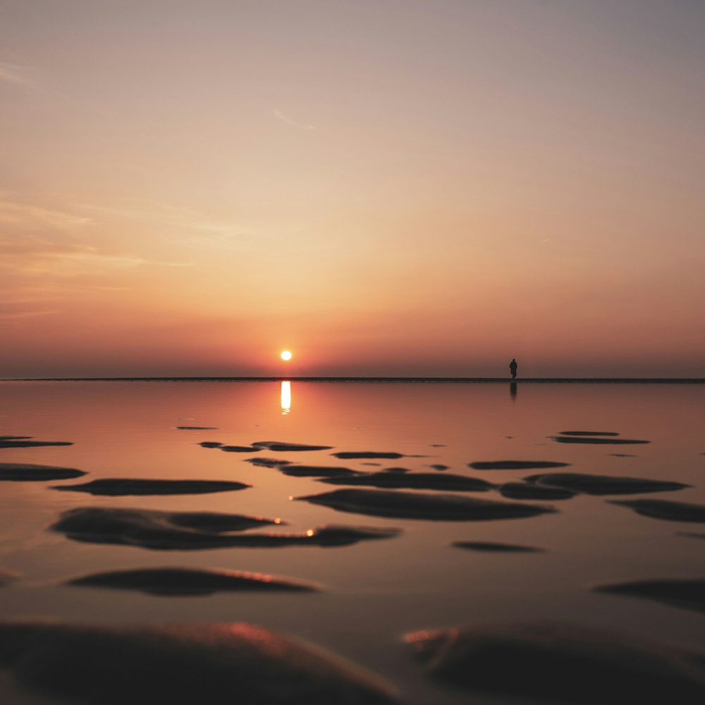 a person standing on a beach at sunset