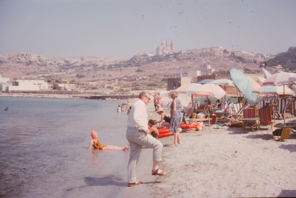 a man standing on a beach next to a body of water