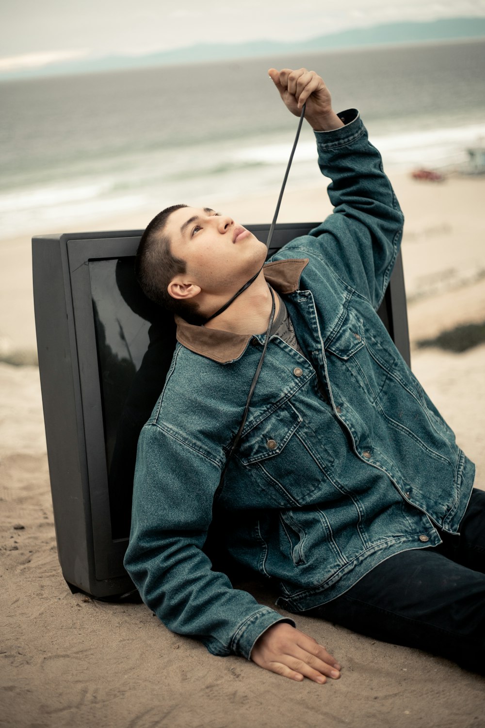man seated on shore leaning on TV