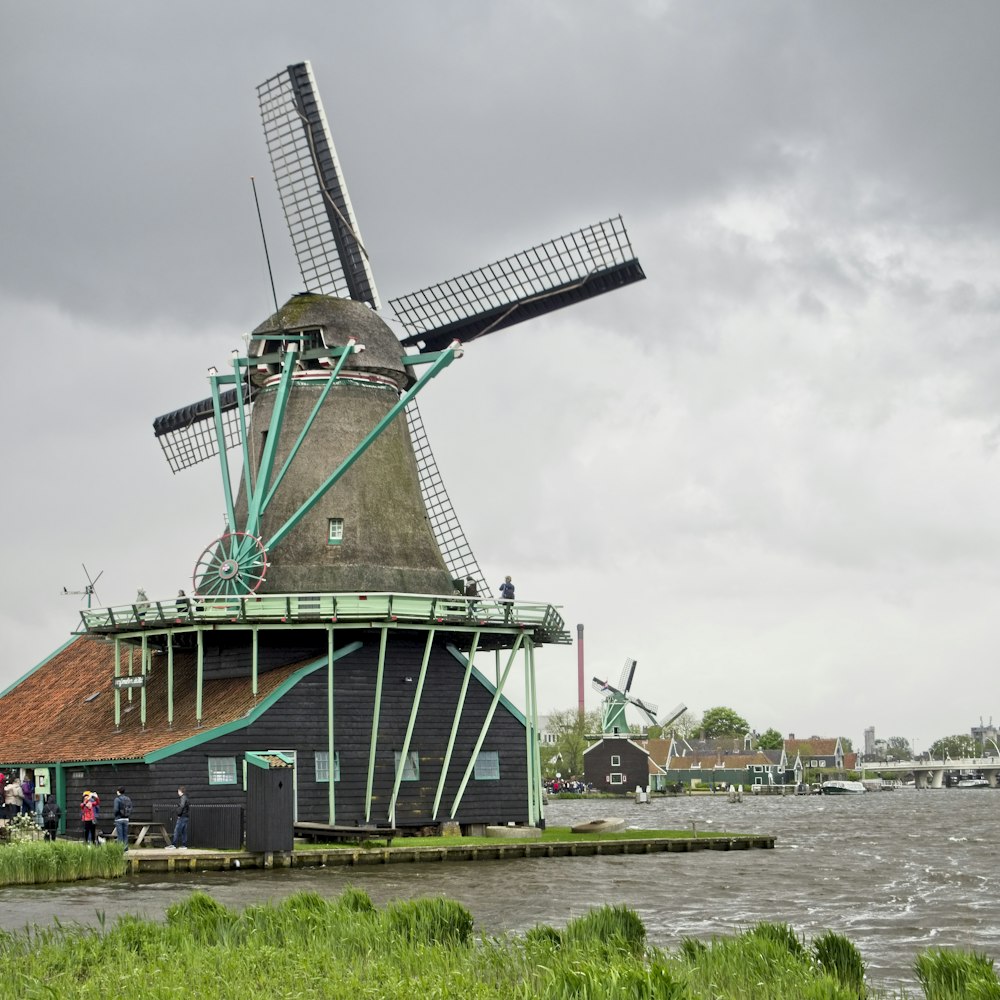 gray and brown windmill beside body of water