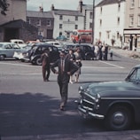 A vintage 1967 street scene with classic cars and people in period attire.