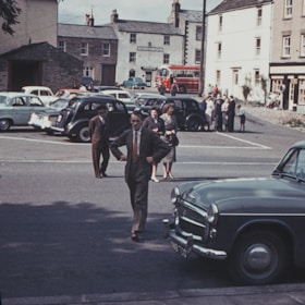 A nostalgic street scene in Poland from 1967, showing classic cars and lively locals.
