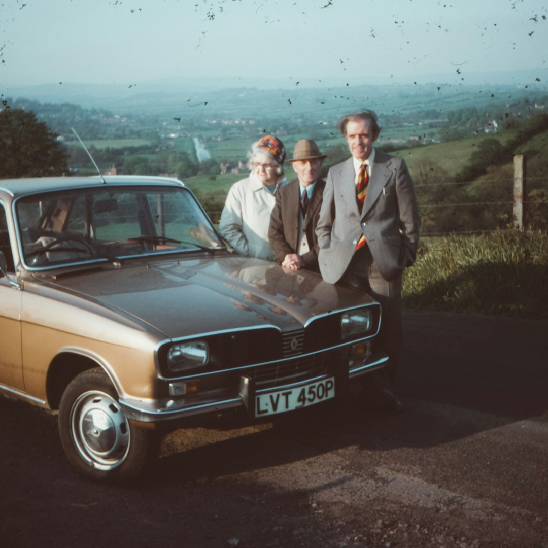 two men and woman standing near brown car