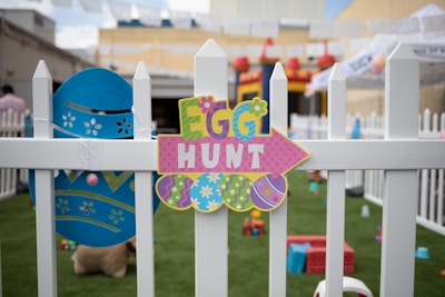 multicolored egg hunt decor on white wooden fence