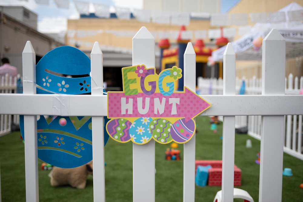 multicolored egg hunt decor on white wooden fence