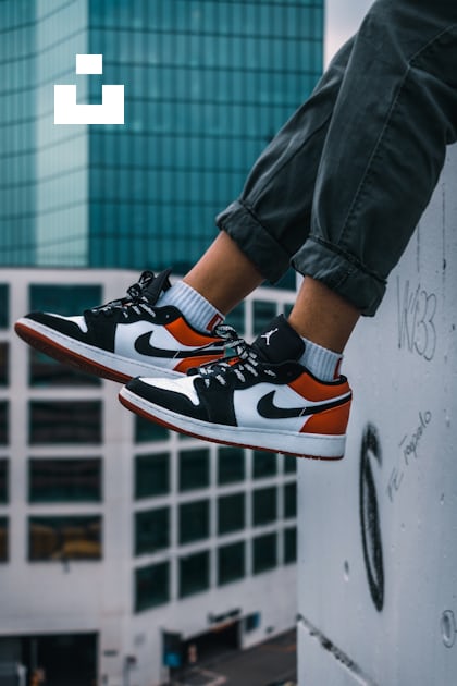 man sitting on the ledge of a building wearing Air Jordan 1 low-top shoes  photo – Free Lightroom Image on Unsplash