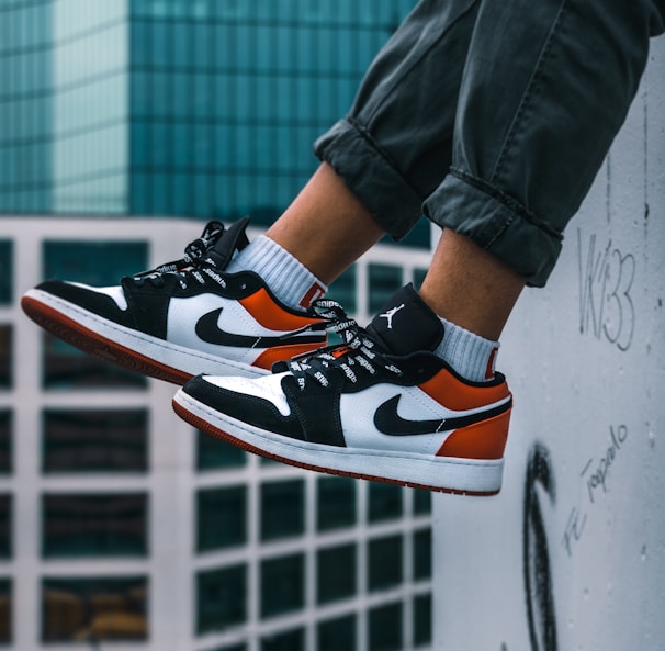 man sitting on the ledge of a building wearing Air Jordan 1 low-top shoes