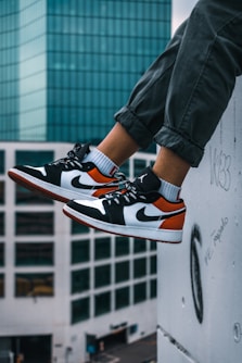 man sitting on the ledge of a building wearing Air Jordan 1 low-top shoes