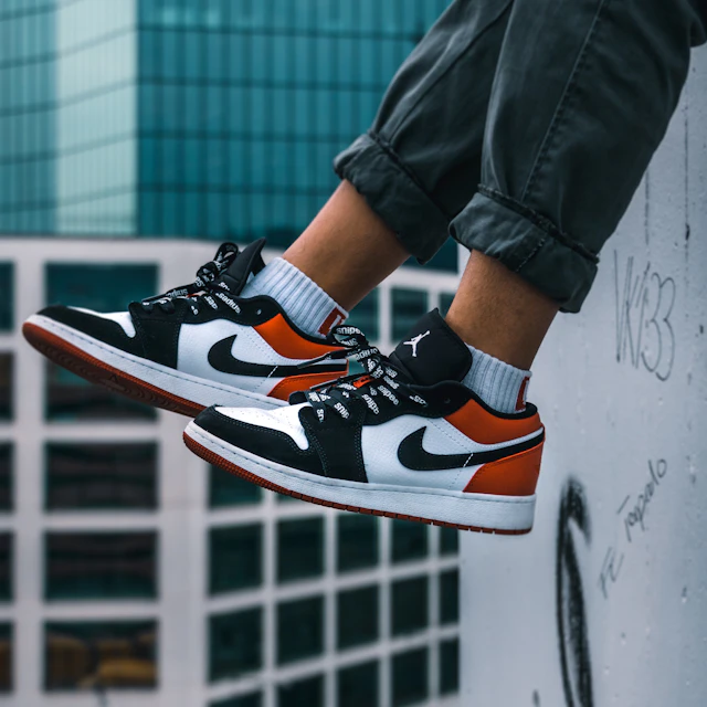 A man sitting on the ledge of a building in Zurich wearing Air Jordan 1 Low sneakers
