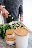 person standing and putting oil on sliced zucchini