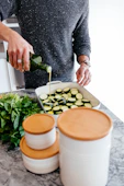 person standing and putting oil on sliced zucchini