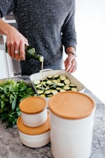 person standing and putting oil on sliced zucchini