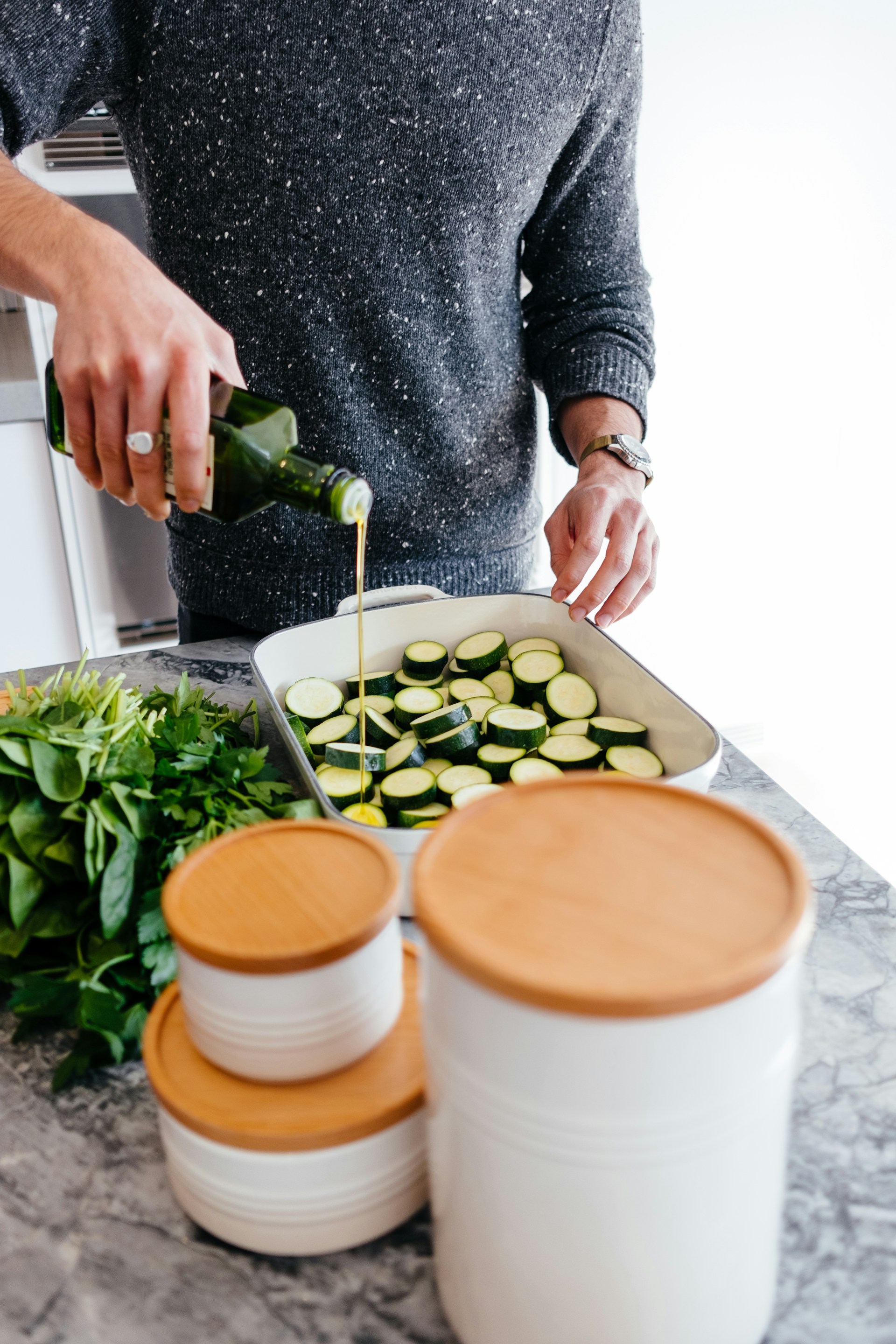 A close-up of a hand drizzling golden olive oil over a plate of roasted seasonal vegetables, warm and inviting.