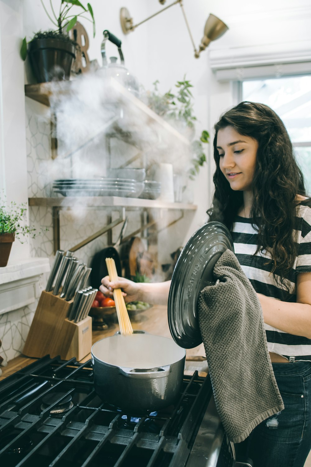 woman holding lid of cooking pot and using brown spatula