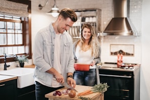 A person chopping fresh vegetables on a wooden cutting board with natural light