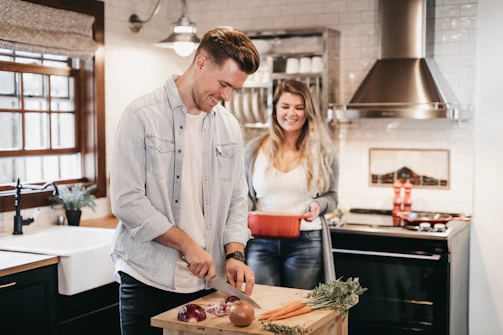 A group of smiling people chopping fresh vegetables in a rustic kitchen.