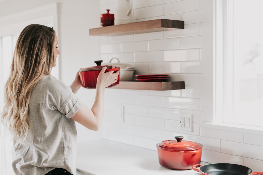 femme tenant des ustensiles de cuisine rouges